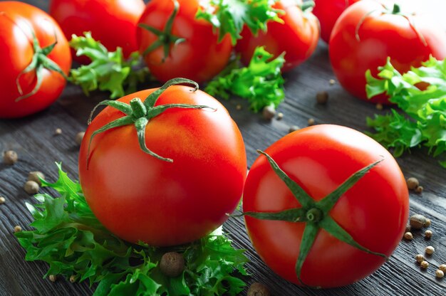 Fresh tomatoes, lettuce and spices on wooden table.