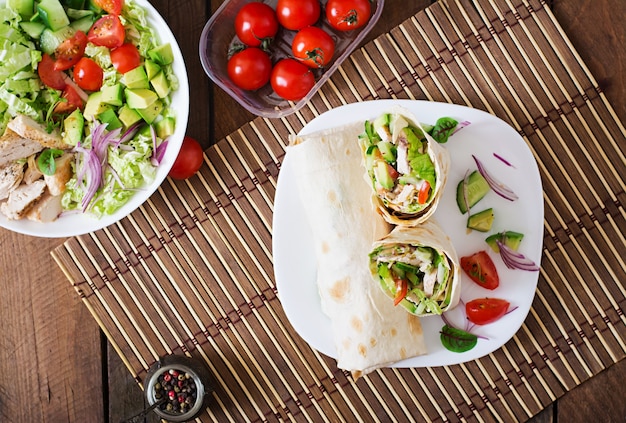 Fresh tortilla wraps with chicken and fresh vegetables on plate. Top view