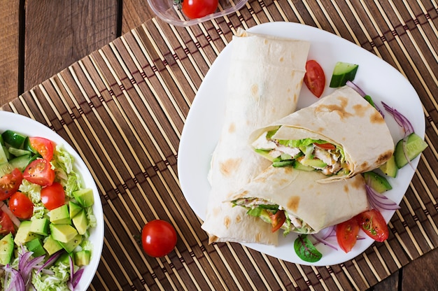 Fresh tortilla wraps with chicken and fresh vegetables on plateTop view