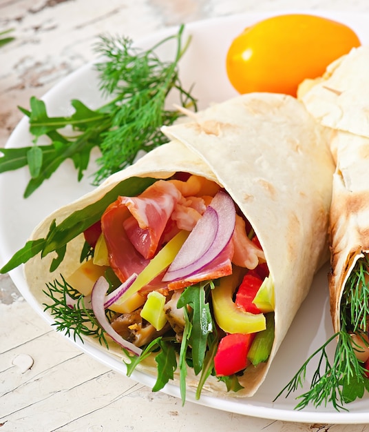 Fresh tortilla wraps with meat and vegetables on plate