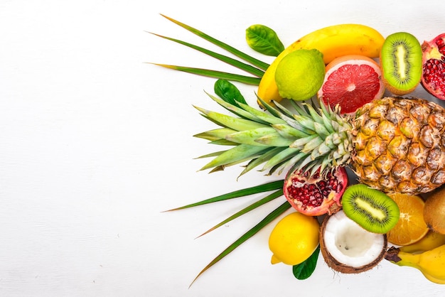 Fresh Tropical Fruits Pineapple coconut kiwi orange pomegranate grapefruit On a wooden background Top view Free space for text