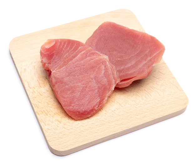 Fresh tuna fish steak on a wooden cutting serving board isolated on a white background