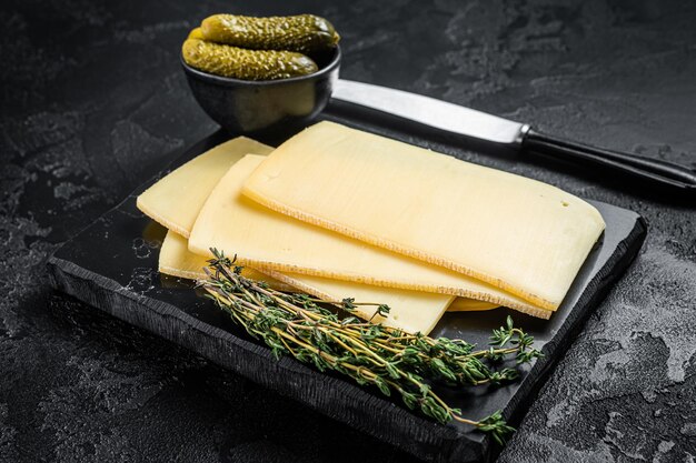 Fresh Uncooked Raclette Swiss cheese slices on marble board Black background Top view