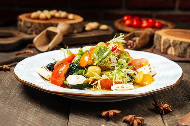 Fresh vegetable mix salad on a white plate on the wooden table