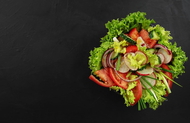 Fresh vegetable salad in a black cup. View from above.