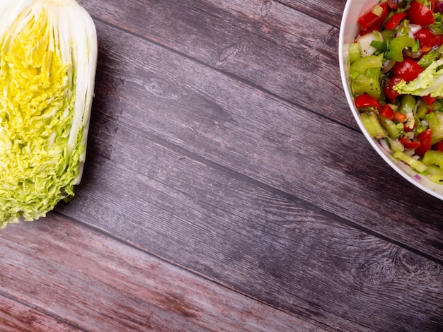 Fresh vegetable salad of chinese cabbage tomato pepper and onion with olive or sunflower oil on wooden table Healthy food