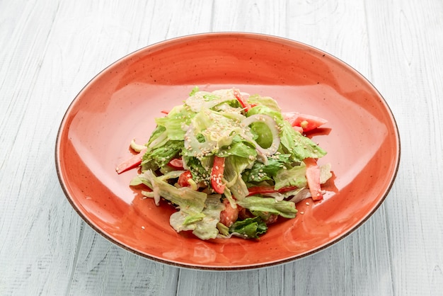 Fresh vegetable salad of chinese cabbage, tomato, pepper and onion with olive or sunflower oil on wooden table.