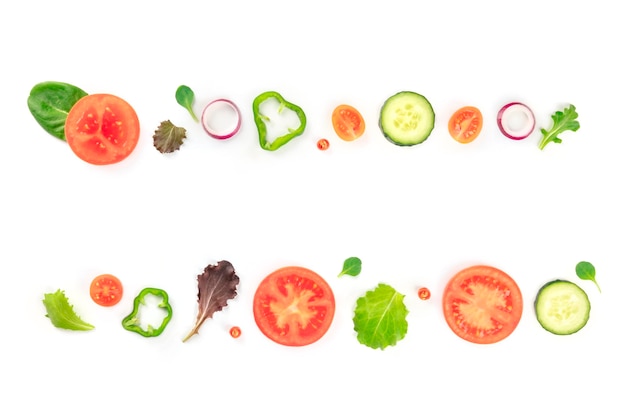 Fresh vegetable salad ingredients shot from above on a white background A flat lay composition with tomato pepper cucumber onion slices and mezclun leaves forming a frame for copy space