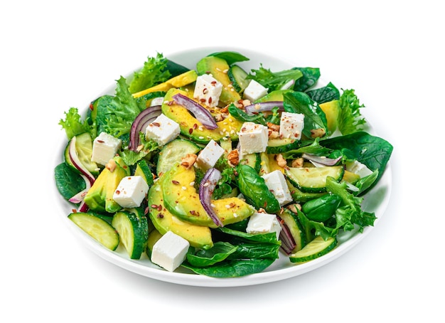 Fresh vegetable salad with avocado cucumber feta and herbs seasoned with nuts and sesame seeds and flax is isolated on a white background Side view Vegetarian food