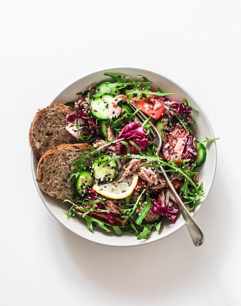 Fresh vegetables arugula radicchio salad with canned tuna on a white background top view Healthy diet food