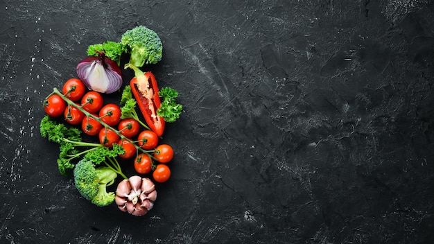 Fresh vegetables on a black background Avocados tomatoes garlic parsley paprika Top view Free space for your text