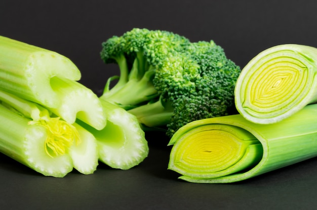 Fresh vegetables: broccoli, celery and leek on black background.