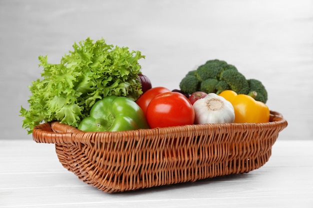 Fresh vegetables in wicker basket on wooden background