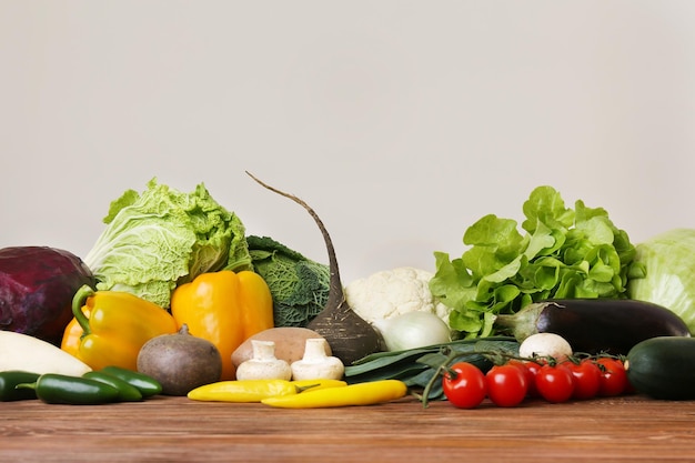 Fresh vegetables on wooden table against light background