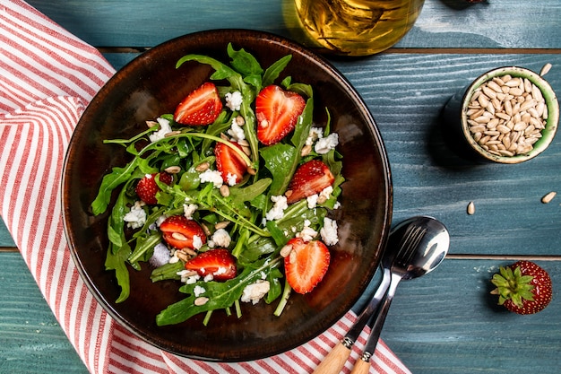 Fresh vegetarian diet salad with strawberries, aragula and cheese. Food recipe background. Close up. top view.