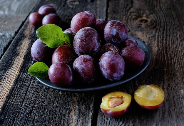  Fresh violet plums at dark wooden table background