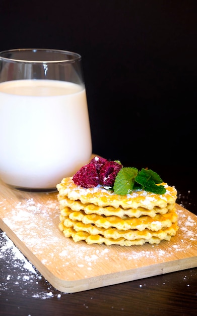 Fresh waffles sprinkled with powdered sugar and garnished with raspberries and mint