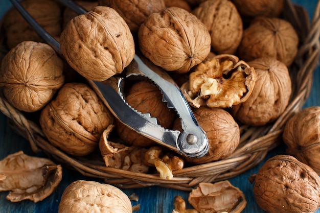 Fresh walnuts with a nutcracker on a blue wooden table