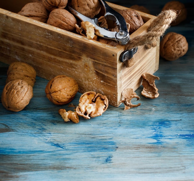 Fresh walnuts with a nutcracker on a blue wooden table