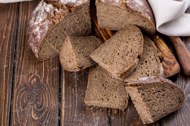 Fresh warm bread cut into pieces an on old wooden board, horizontal