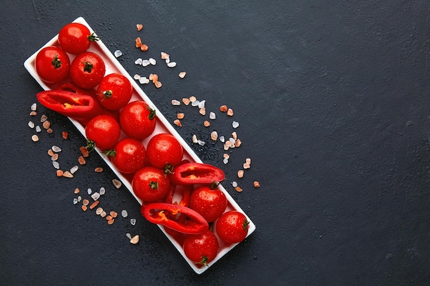 Fresh washed cherry tomatoes and paprika slices on a white oblon