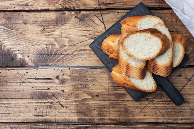 Fresh white bread baguette cut slays on a wooden cutting Board. Copy space.