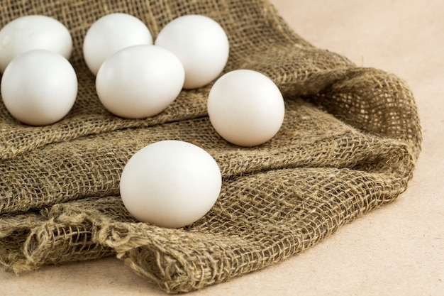 Fresh white eggs on burlap textile at rustic background 