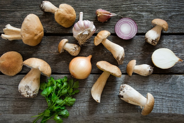 Fresh white mushrooms with parsley and garlic on wooden board. Top view.