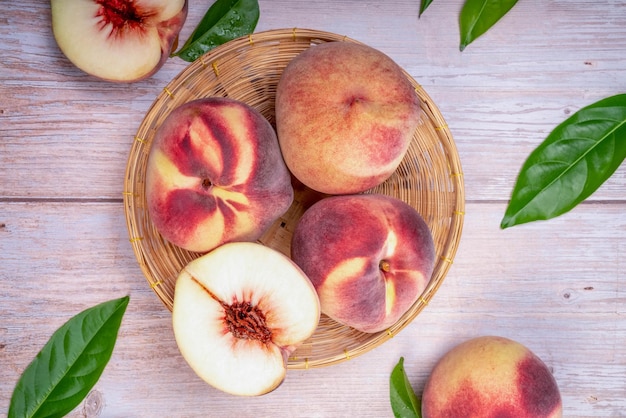 Fresh white Peaches with leaves on the old wooden background