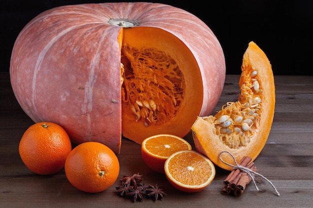 Fresh whole organic pumpkin orange halves and cinnamon sticks on a dark background