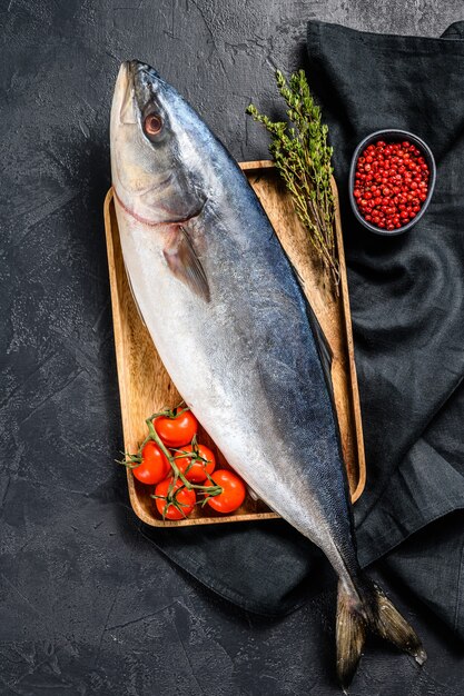 Fresh whole raw Japanese yellowtail with tomato and herbs