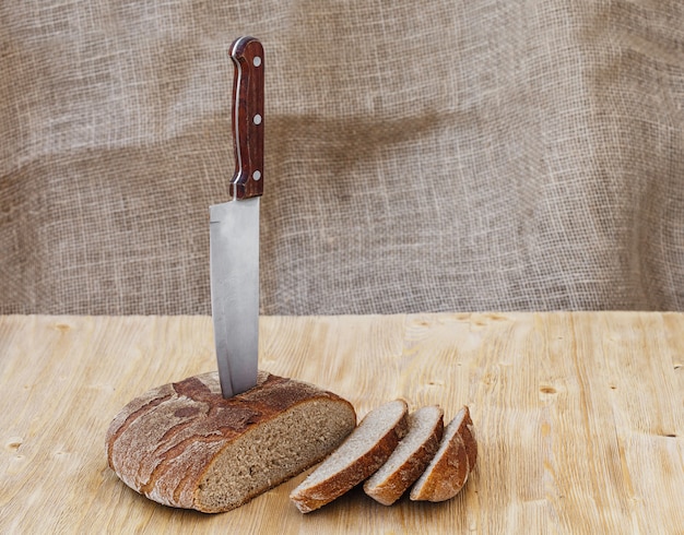 Fresh whole rye bread on a wooden table with knife