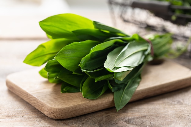 Fresh wild leek leaves on a wooden board. Useful properties of ramson. Leaves of fresh ramson.