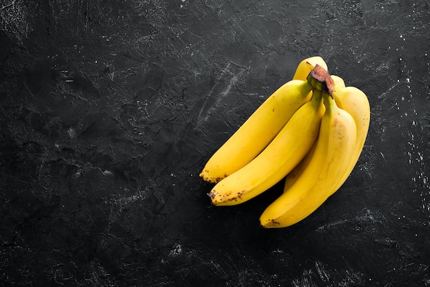 Fresh yellow bananas on a black stone table Top view Free copy space