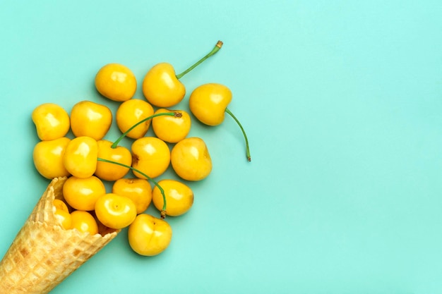 Fresh yellow cherries in waffle cones on green background