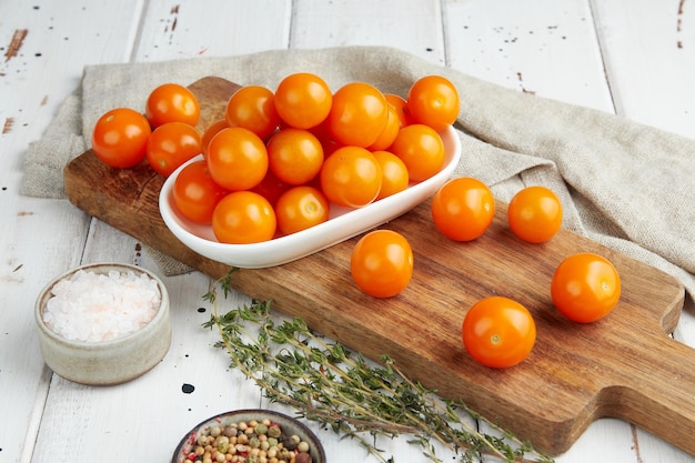 Fresh yellow cherry tomatoes on white wooden background