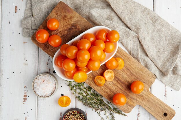 Fresh yellow cherry tomatoes on white wooden background