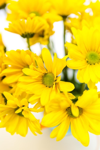 Fresh yellow flowers in a small bouquet in glass jar.