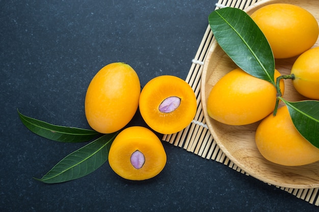 Fresh yellow marian plum fruit (Mayongchid) in Thai name) on black stone. Top view