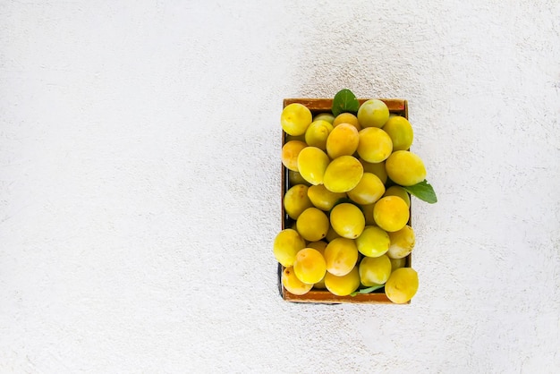 Fresh yellow plums Ripe fruits in a wooden box on white background