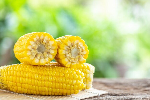 Fresh yellow sweet corn on wooden table with green blur light background