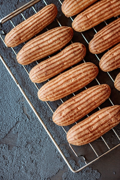 Freshly baked aromatic custard cakes cool on the wire rack on a dark textured background