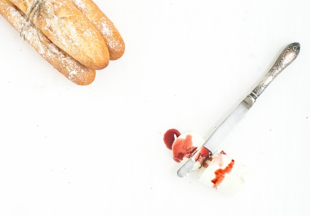 Freshly baked baguettes, a piece of goat cheese with jam and a knife