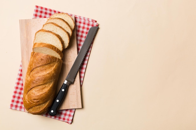 Freshly baked bread cut with knife on a wooden board top view Sliced bread and knife