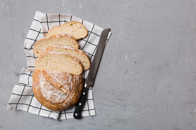 Freshly baked bread cut with knife on a wooden board top view Sliced bread and knife