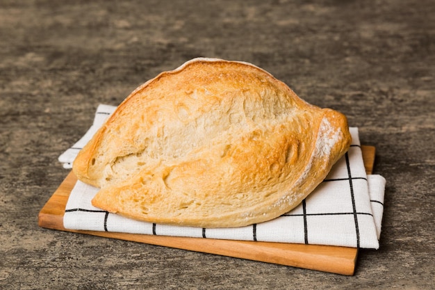 Freshly baked bread on cutting board against white wooden background perspective view bread with copy space