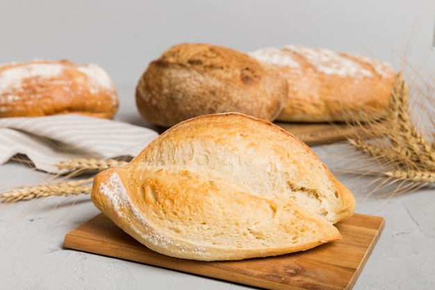 Freshly baked bread on cutting board against white wooden background perspective view bread with copy space