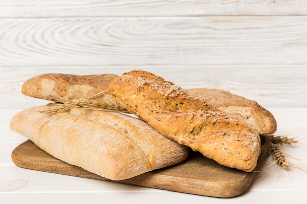 Freshly baked bread on cutting board against white wooden background perspective view bread with copy space