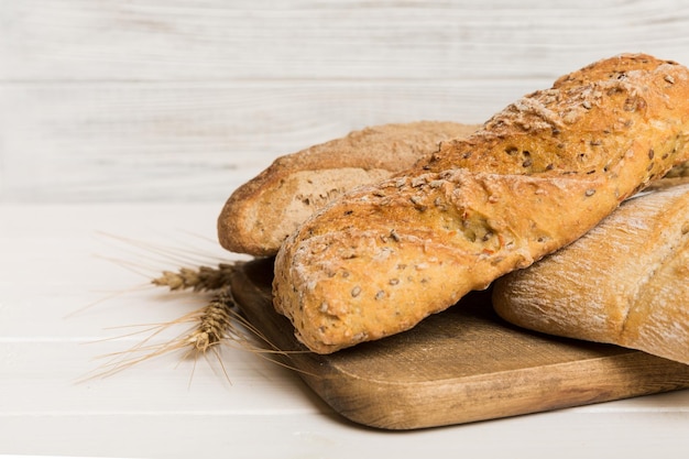 Freshly baked bread on cutting board against white wooden background perspective view bread with copy space