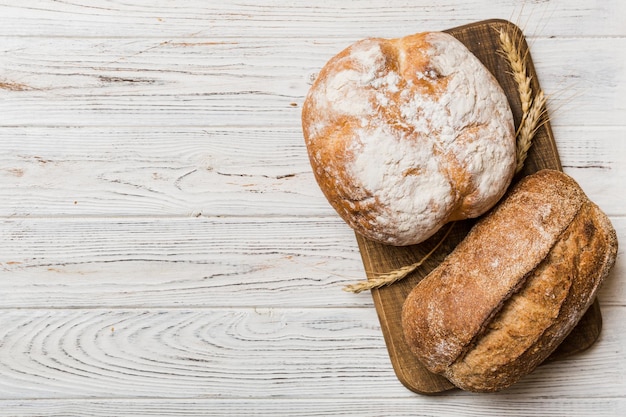 Freshly baked bread on cutting board against white wooden background top view bread with copy space